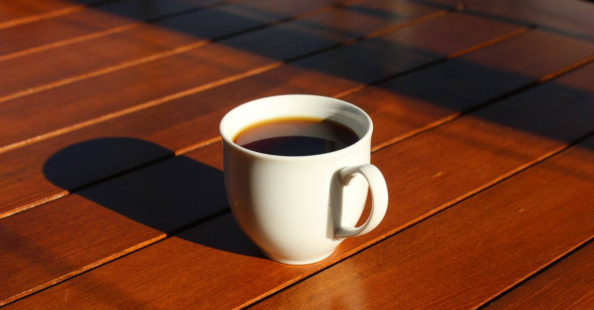Ceramic cup on a wooden table next to a window with morning light
