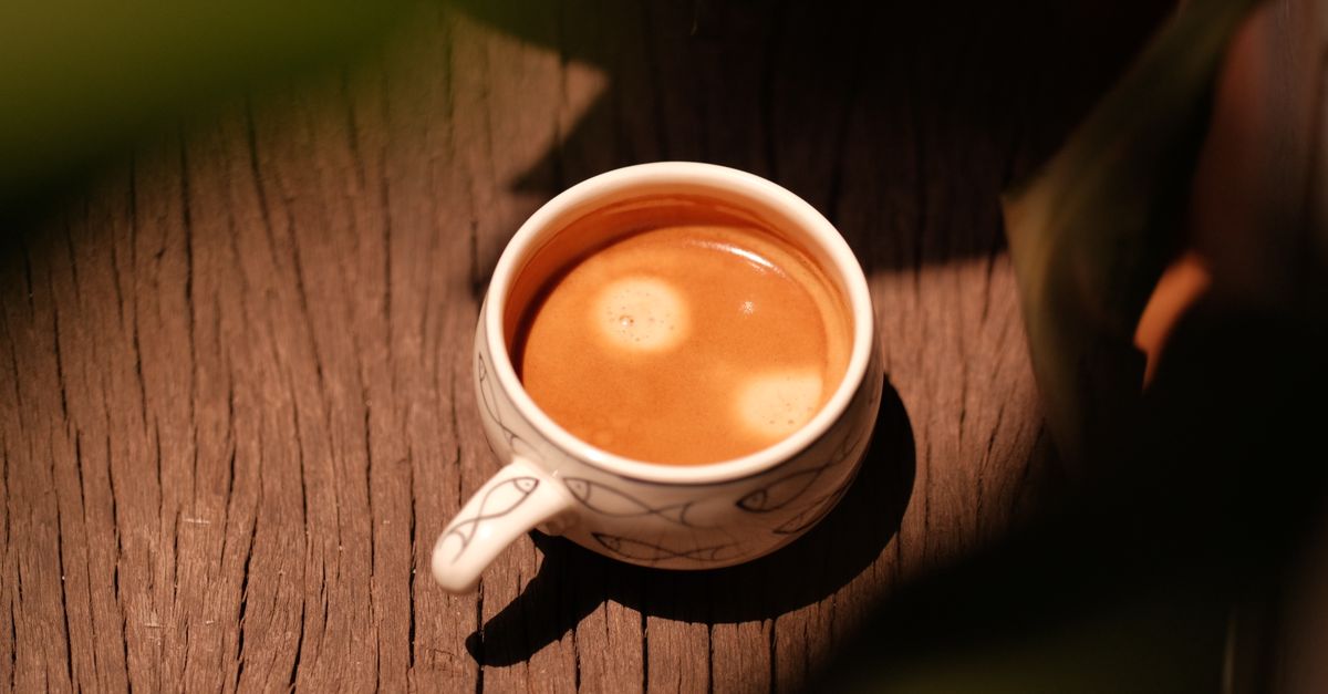 Ceramic cup on a wooden table next to a window with morning light