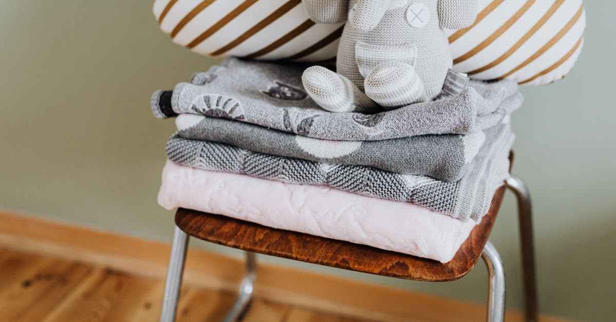 Wooden chair next to a window with a folded blanket over the armrest