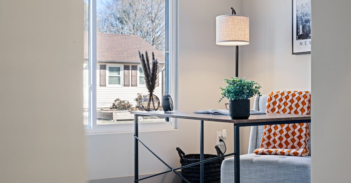Chair next to a warm lamp and a folded blanket in a corner of a home
