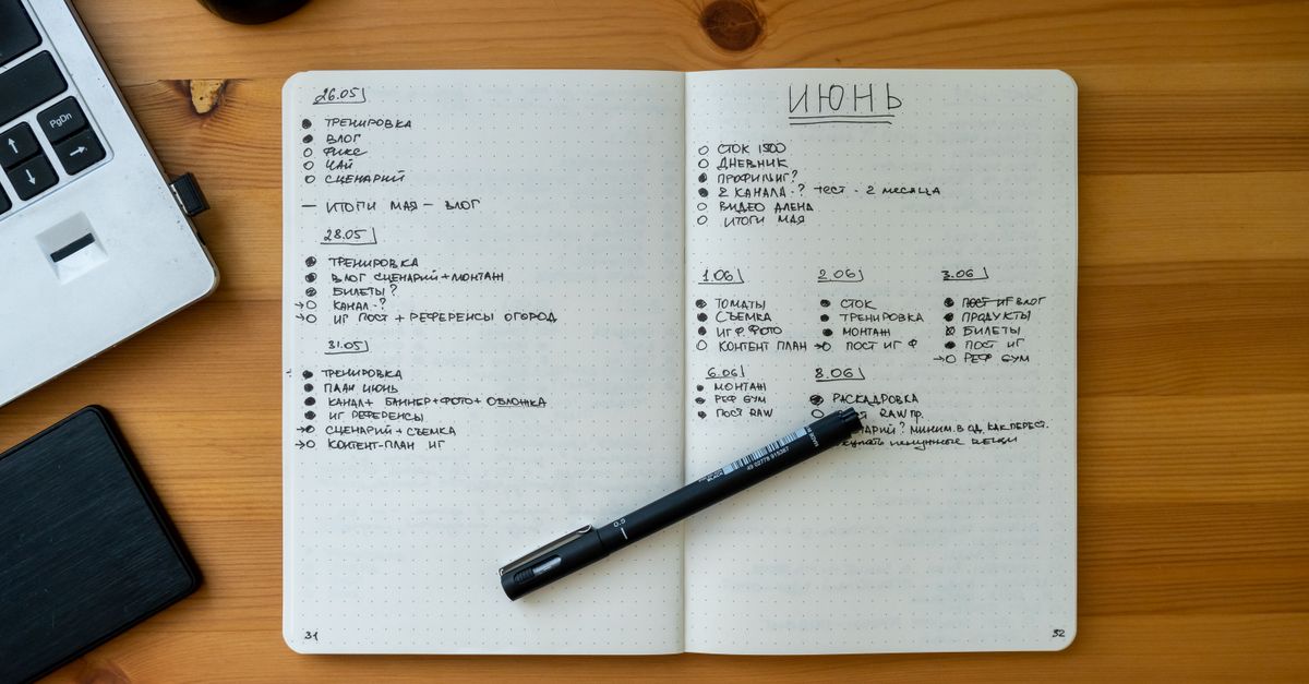Notebook with short notes of three or four words next to a pen on wood