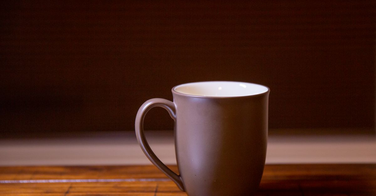Ceramic cup on a wooden table next to a window with morning light
