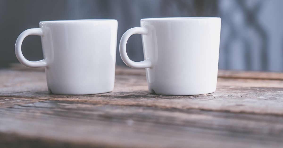 Ceramic cup on a wooden table next to a window with morning light