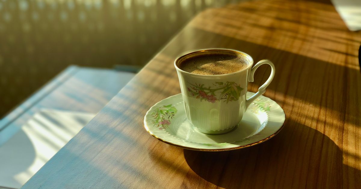 Ceramic cup on a wooden table next to a window with morning light